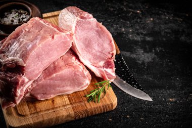 Raw pork on a spice cutting board. On a black background. High quality photo