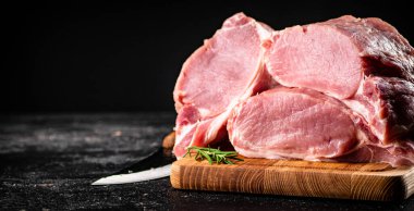 Large chunks of raw pork on a wooden cutting board. On a black background. High quality photo