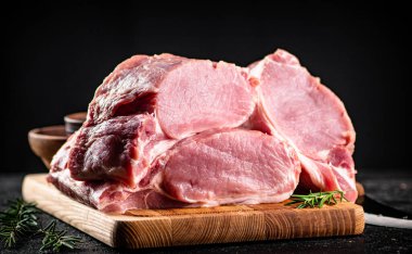 Large chunks of raw pork on a wooden cutting board. On a black background. High quality photo