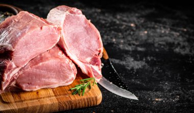 Large chunks of raw pork on a wooden cutting board. On a black background. High quality photo