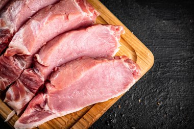 Raw pork sliced on a wooden cutting board. On a black background. High quality photo