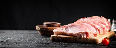 Raw pork on a spice cutting board. On a black background. High quality photo