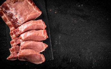 Pieces of raw pork on a stone board. On a black background. High quality photo