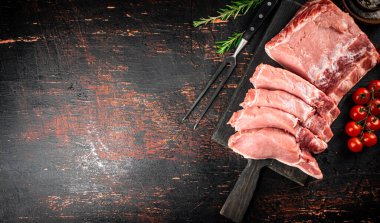 Sliced pork raw on a cutting board. On a rustic dark background. High quality photo