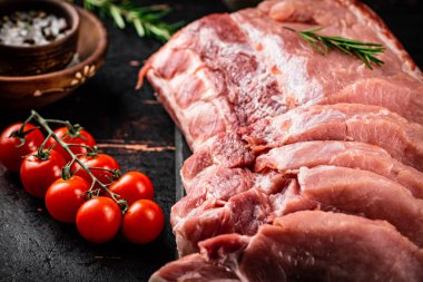 Sliced pork raw on a cutting board. On a rustic dark background. High quality photo