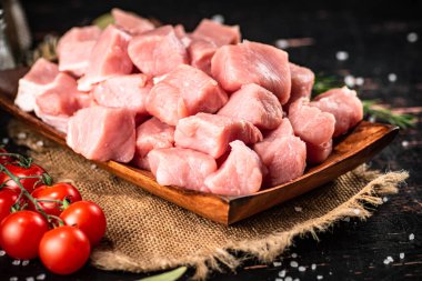 Chopped raw pork with a sprig of cherry tomatoes. On a black background. High quality photo