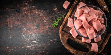 Pieces of raw pork in a bowl on a cutting board. Against a dark background. High quality photo