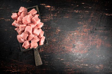 Pieces of raw pork on a cutting board on the table. On a rustic dark background. High quality photo