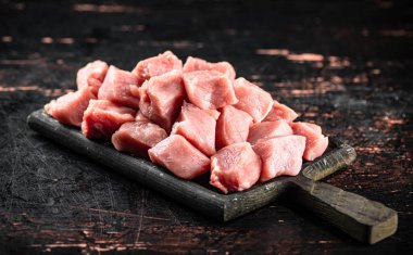 Pieces of raw pork on a cutting board on the table. On a rustic dark background. High quality photo