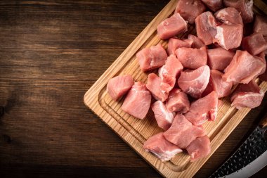 Pieces of raw pork on a cutting board. On a wooden background. High quality photo