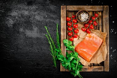 Salted salmon with parsley and tomatoes on a wooden tray. On a black background. High quality photo