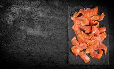 Pieces of salted salmon on a stone board. On a black background. High quality photo