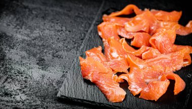 Pieces of salted salmon on a stone board. On a black background. High quality photo