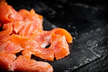 Pieces of salted salmon on a stone board. On a black background. High quality photo