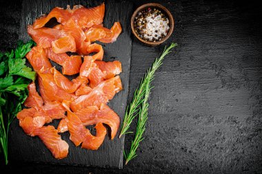 Salted salmon on a stone board with spices. On a black background. High quality photo