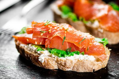 Sandwich with salmon and herbs. Against a dark background. High quality photo