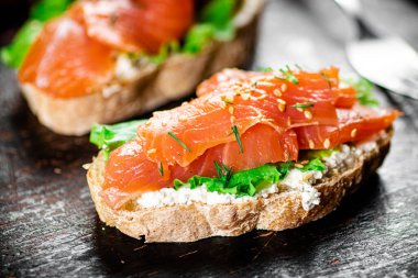 Sandwich with salmon and herbs. Against a dark background. High quality photo