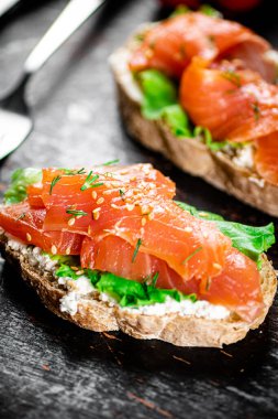 Sandwich with salmon and herbs. Against a dark background. High quality photo