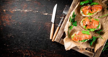 Salmon sandwich on a wooden tray. Against a dark background. High quality photo