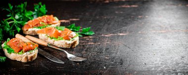 Sandwich with pieces of salmon and greens. Against a dark background. High quality photo