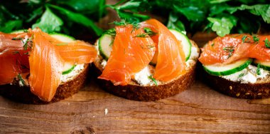 Delicious sandwich with salmon and parsley. On a wooden background. High quality photo