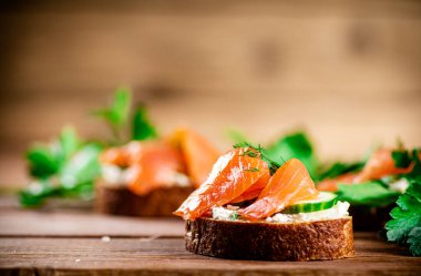 Delicious sandwich with salmon and parsley. On a wooden background. High quality photo