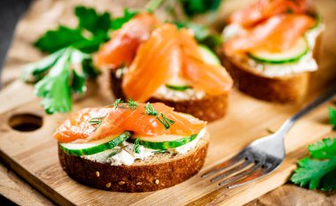 Salmon sandwich on a cutting board. On a black background. High quality photo