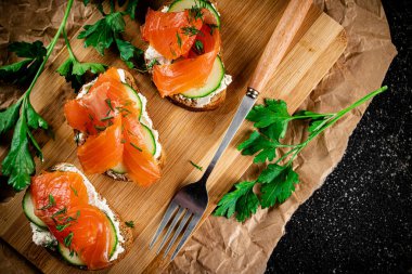 Salmon sandwich on a cutting board. On a black background. High quality photo