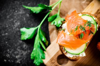 Salmon sandwich on a cutting board. On a black background. High quality photo