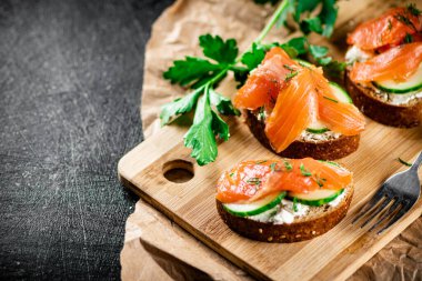 Salmon sandwich on a cutting board. On a black background. High quality photo