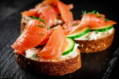Salmon sandwich on a stone board. On a black background. High quality photo
