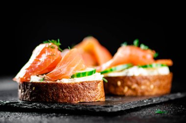 Salmon sandwich on a stone board. On a black background. High quality photo