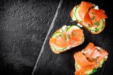 Salmon sandwich on a stone board. On a black background. High quality photo