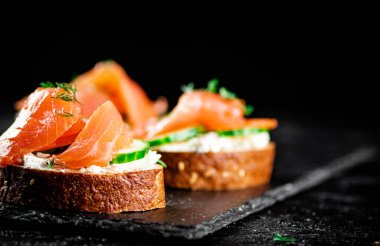 Salmon sandwich on a stone board. On a black background. High quality photo
