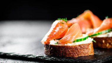 Salmon sandwich on a stone board. On a black background. High quality photo