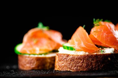 Salmon sandwich on the table. On a black background. High quality photo
