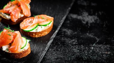 Salmon sandwich on a stone board. On a black background. High quality photo