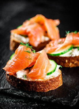 Salmon sandwich on a stone board. On a black background. High quality photo