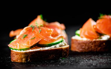 Salmon sandwich on the table. On a black background. High quality photo
