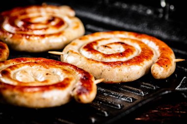 Grilled sausages in a frying pan. On a black background. High quality photo