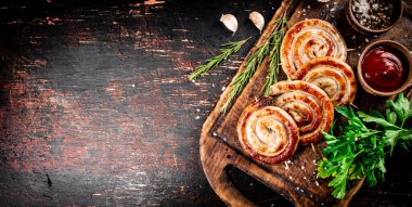 Grilled sausages on a cutting board with tomato sauce, garlic and herbs. Against a dark background. High quality photo
