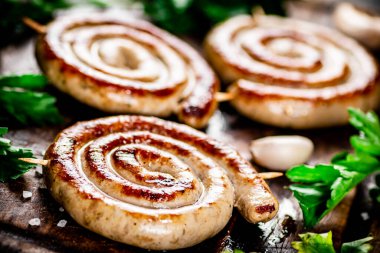 Grilled sausages with garlic and parsley on a wooden background. High quality photo