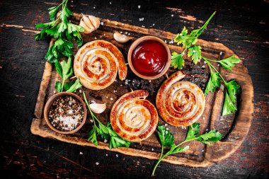 Grilled sausages with parsley and tomato sauce. Against a dark background. High quality photo
