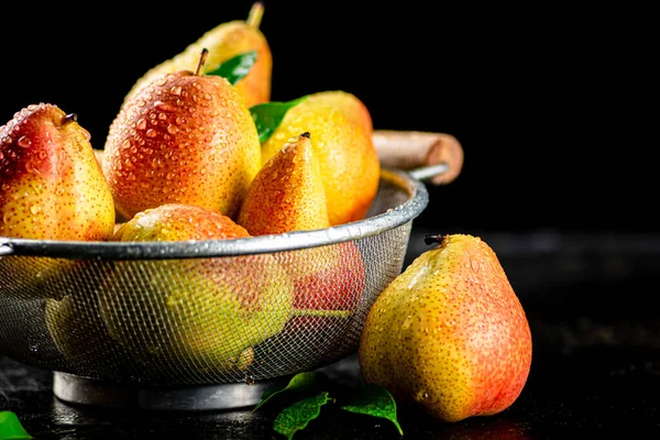 Juicy pears in a colander with foliage. On a black background. High quality photo