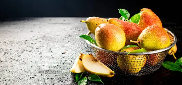 Fresh pears with leaves in a colander. On a black background. High quality photo