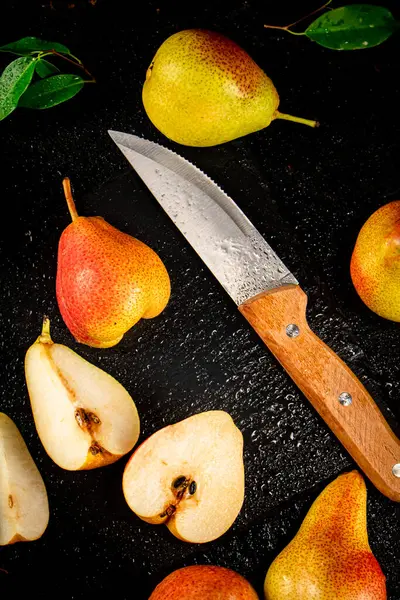 Sliced ripe pear with a knife. On a black background. High quality photo