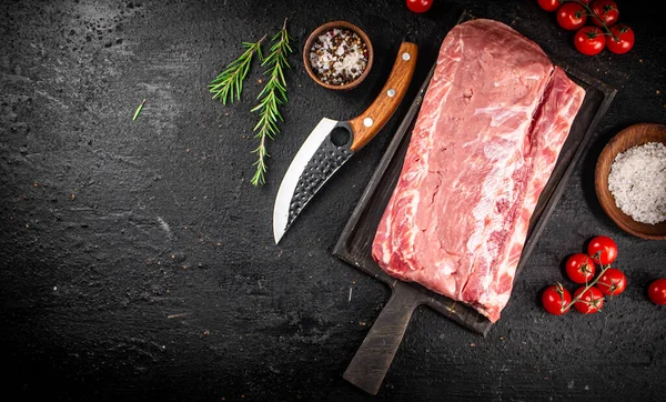 Raw pork on a cutting board with spices and a knife. On a black background. High quality photo