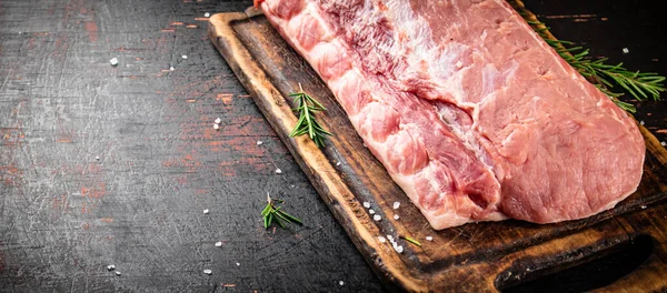Piece Raw Pork Cutting Board Sprig Rosemary Rustic Dark Background — Stockfoto