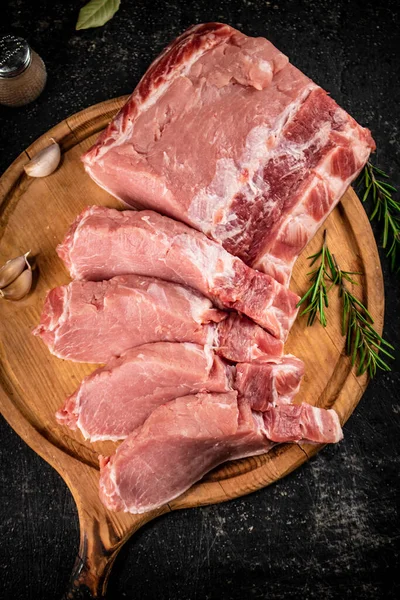 stock image Fresh raw pork on a cutting board with rosemary. On a black background. High quality photo