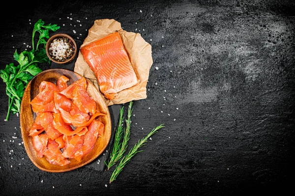 Salted salmon with rosemary, parsley and spices. On a black background. High quality photo